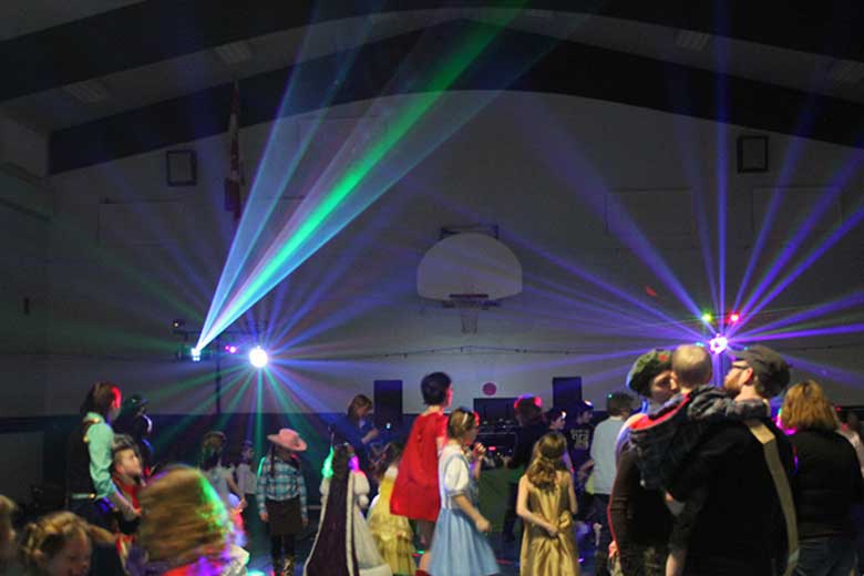 School Laser Light Show, DJ Hamilton, Family Dance Guests dancing with blue, purple, green and pink beams coming from the light show and laser light show. Taken in Hamilton Ontario.